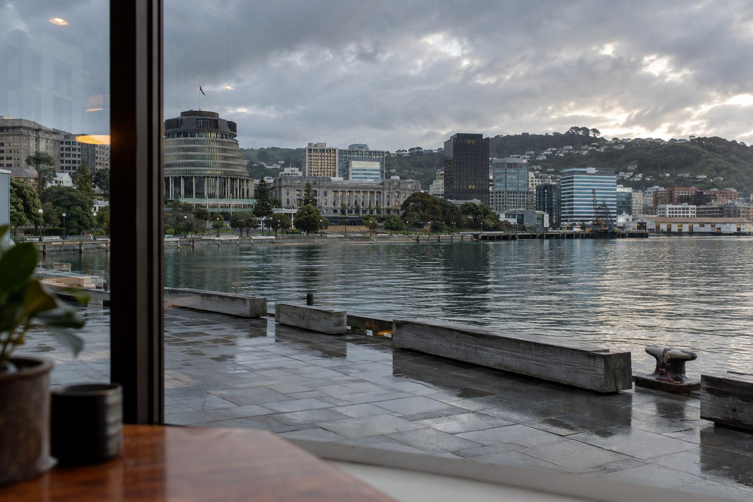 Wellington waterfront on a cloudy afternoon with civic buildings and wet stone promenade, no people